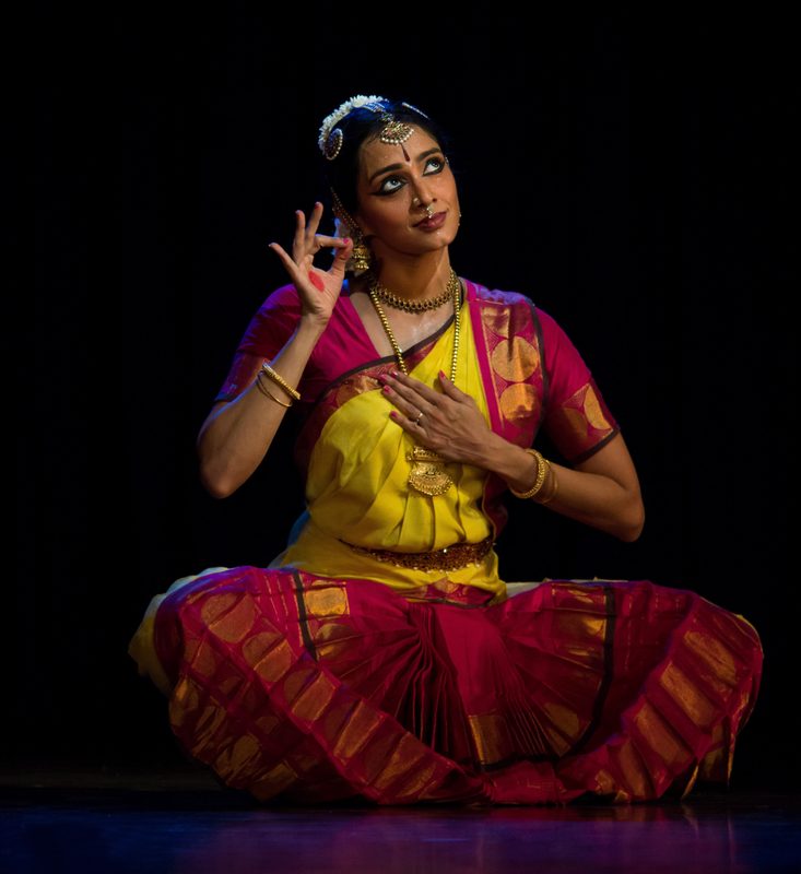 Lakshmi seated in a yellow and crimson costume, mid-abhinaya