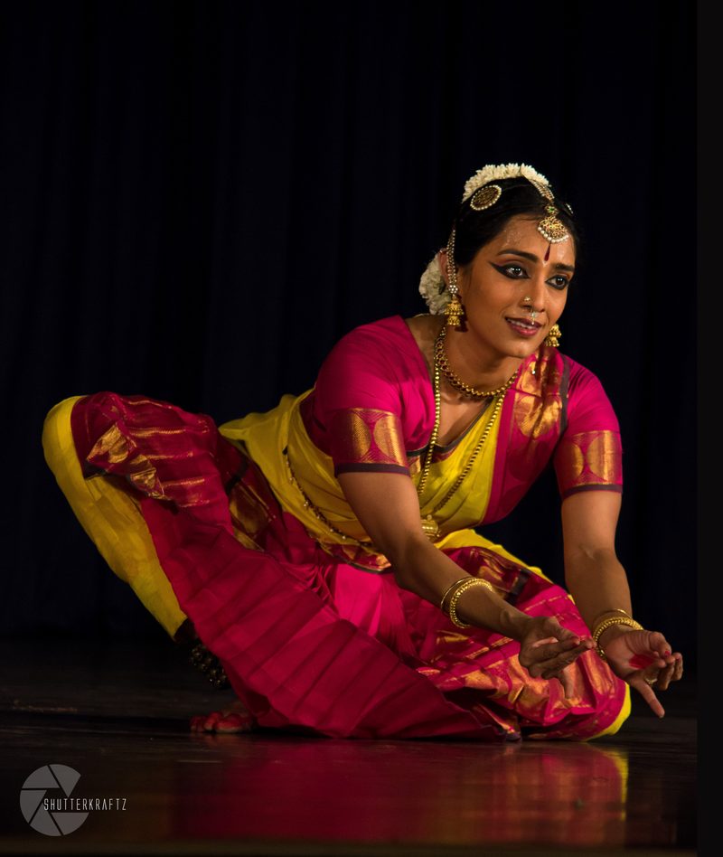 Seated low in yellow and pink, smiling